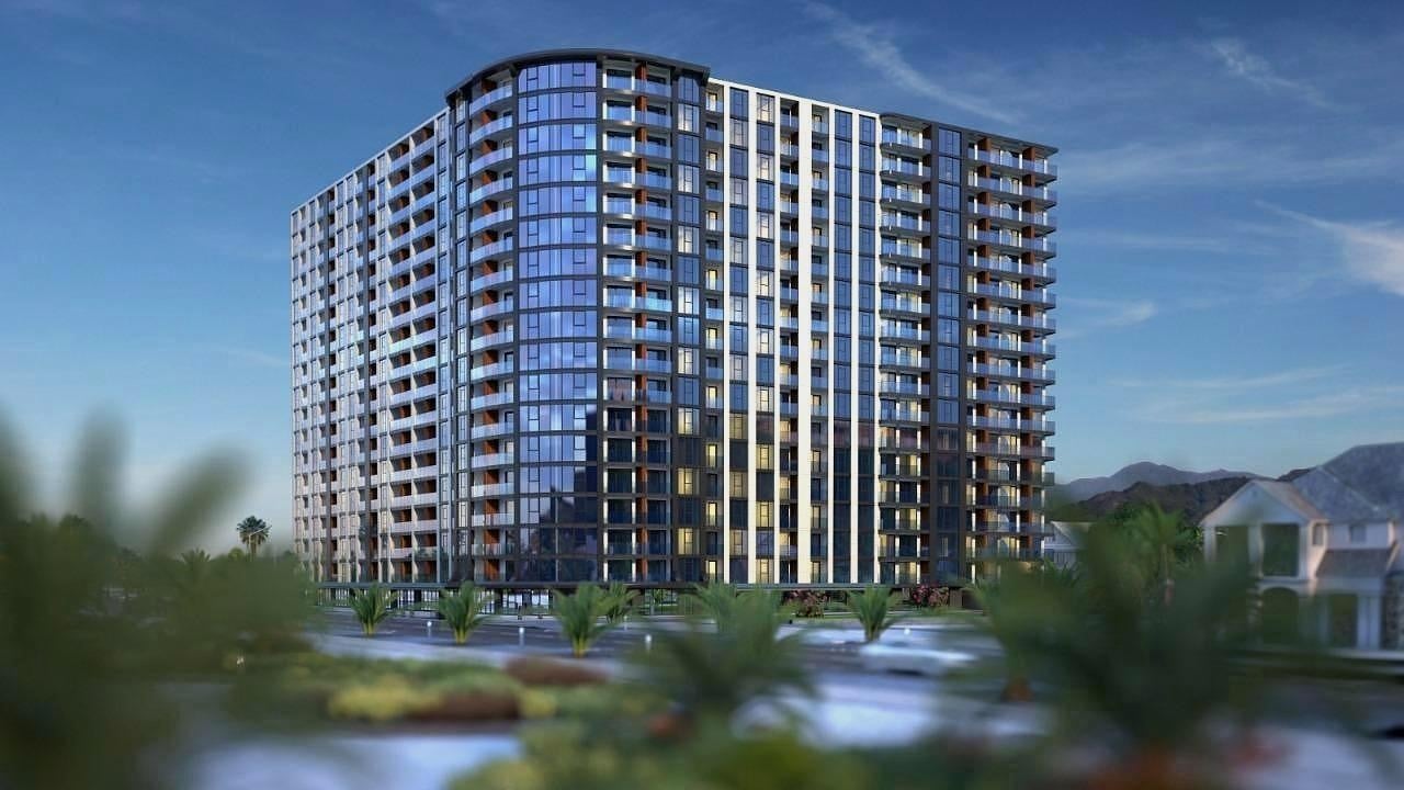 Архитектурная 3D-визуализация современного многоэтажного жилого комплекса с панорамным остеклением и благоустроенной территорией.